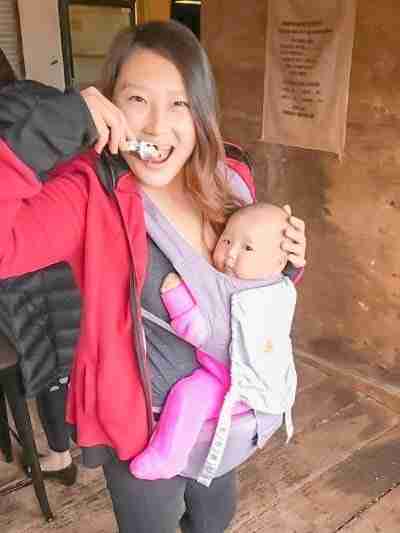 Girl eating oyster with baby in carrier