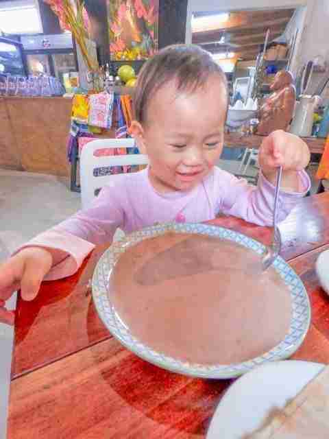 Little Kyra pouring hot chocolate into a plate and happily playing with it