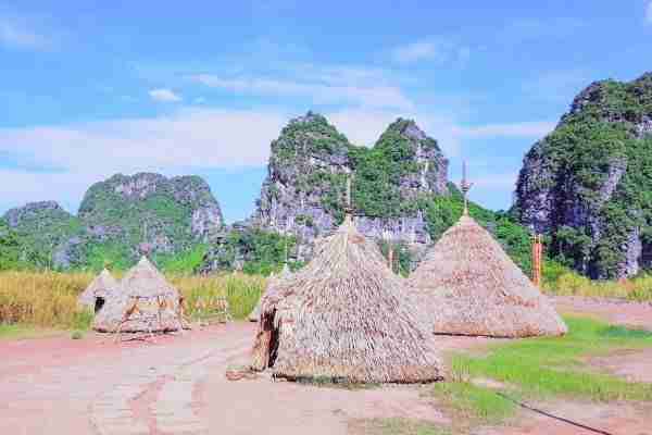 Tribal village Kong Skull Island film location with mountain backdrop and blue sky